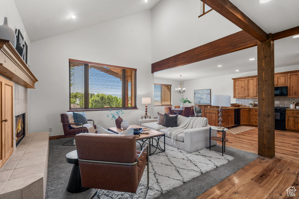 Living room featuring recessed lighting, light wood-type flooring, a fireplace, a chandelier, and high vaulted ceiling