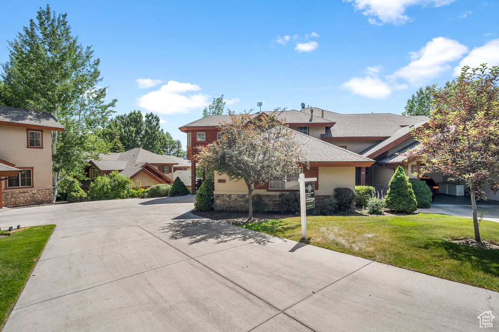 View of front of house featuring stone siding, a front yard, driveway, and a shingled roof