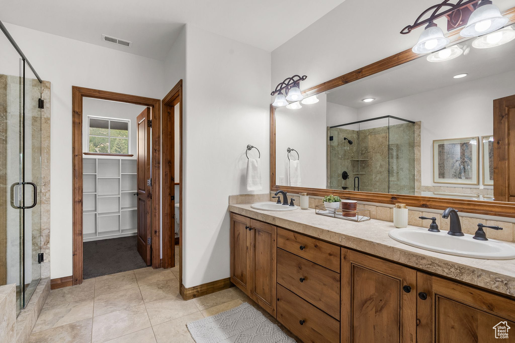 Full bath with a stall shower, double vanity, and tile patterned floors