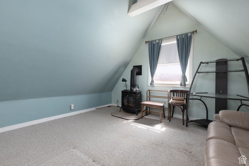 Sitting room featuring baseboards, carpet, lofted ceiling, and a wood stove