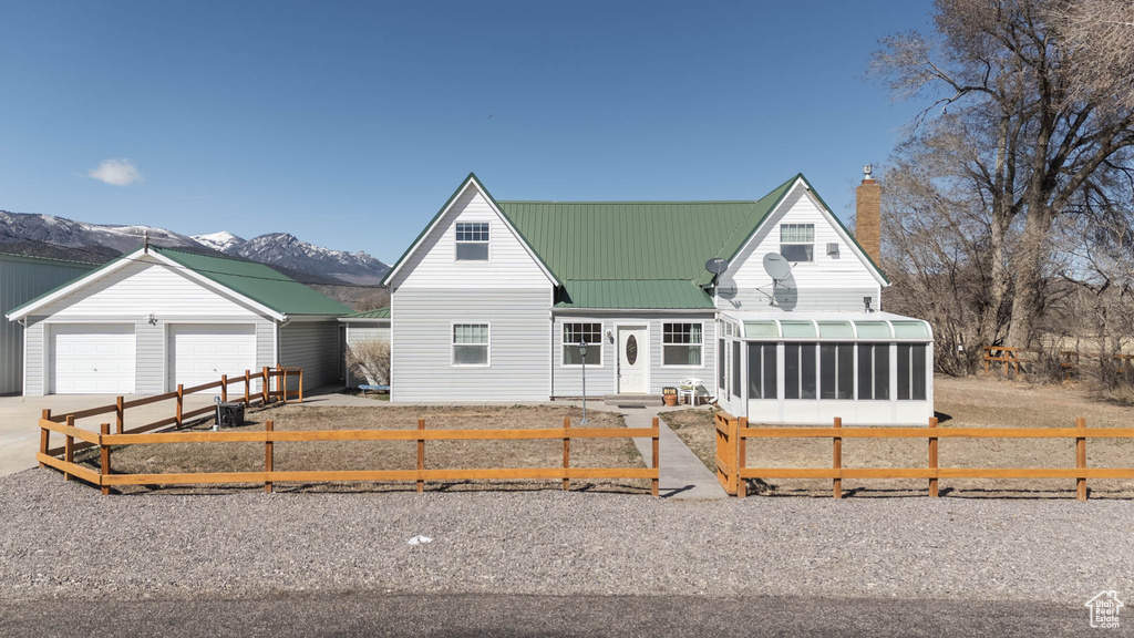 View of front of property with a fenced front yard, a chimney, metal roof, an outdoor structure, and a sunroom