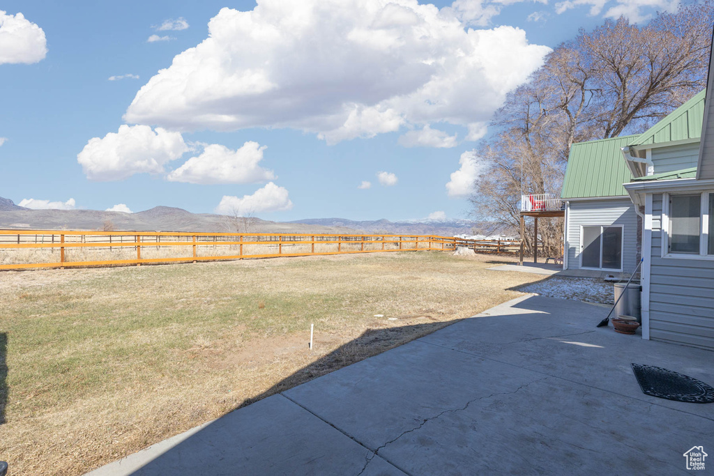 View of yard featuring a patio area, fence, and a mountain view
