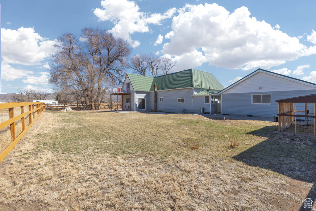 Rear view of house with a lawn, fence, and metal roof
