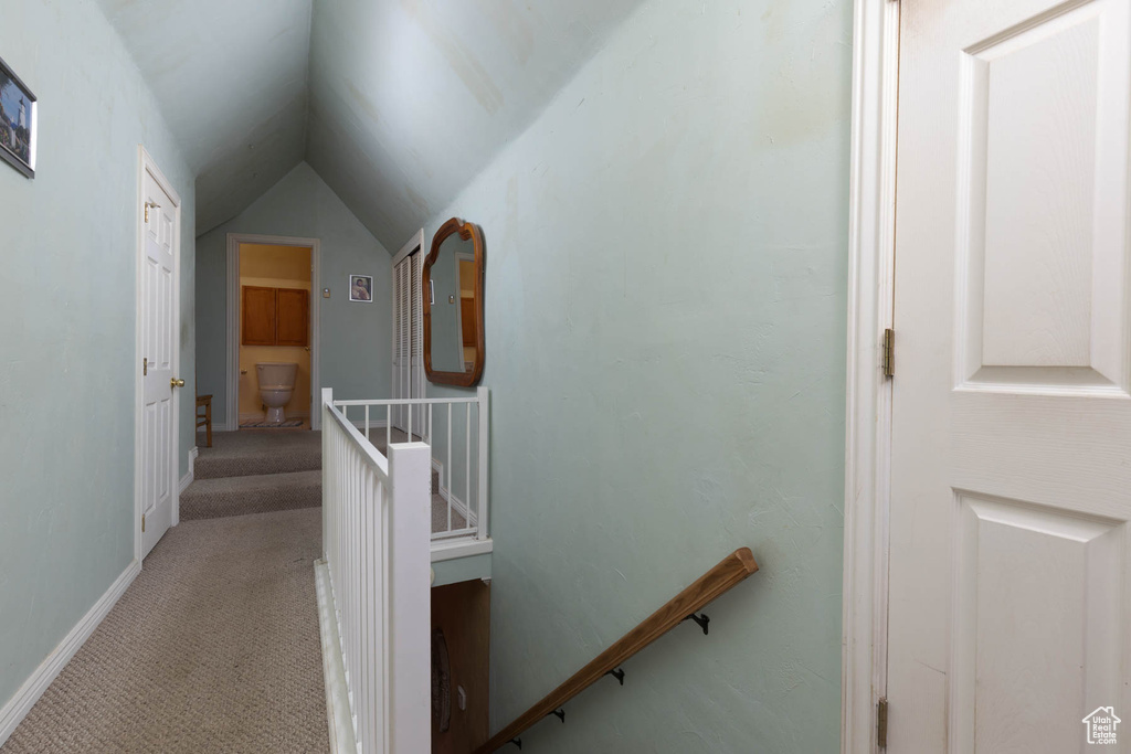 Corridor with lofted ceiling, an upstairs landing, carpet, and baseboards