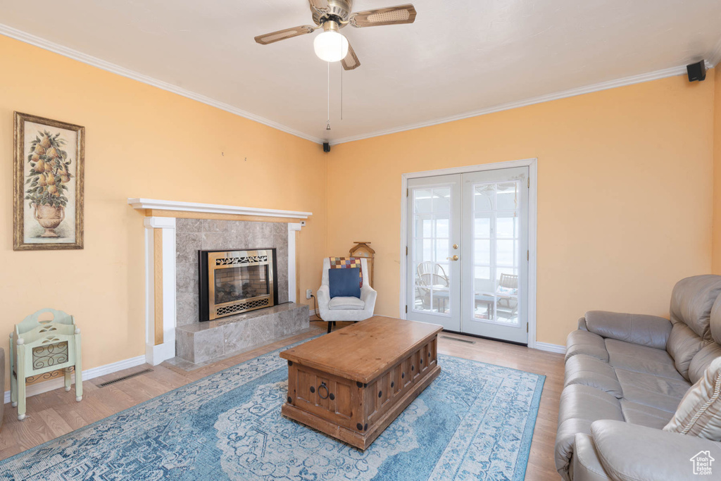Living room with crown molding, a premium fireplace, and ceiling fan