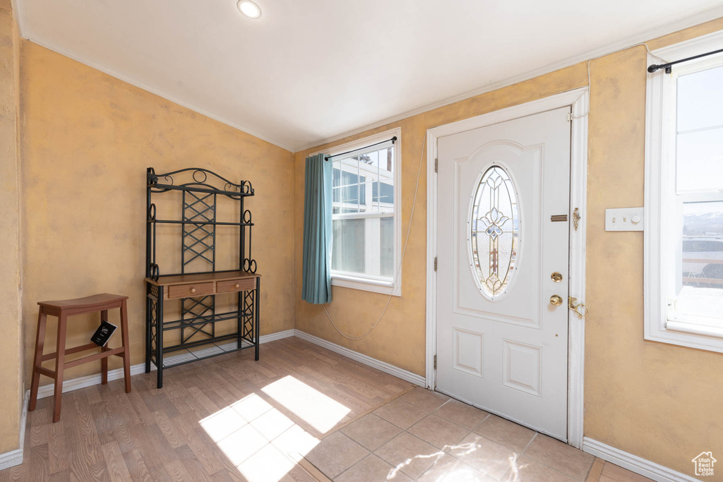 Foyer with vaulted ceiling, baseboards, and wood finished floors