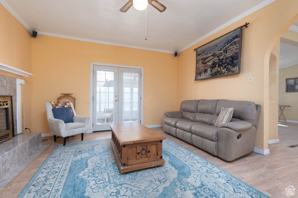 Living area featuring arched walkways, light wood finished floors, ceiling fan, and ornamental molding
