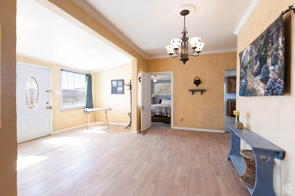 Entryway featuring a notable chandelier, light wood-style floors, baseboards, and ornamental molding
