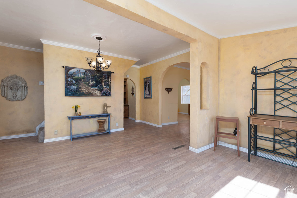 Interior space featuring baseboards, arched walkways, an inviting chandelier, and wood finished floors