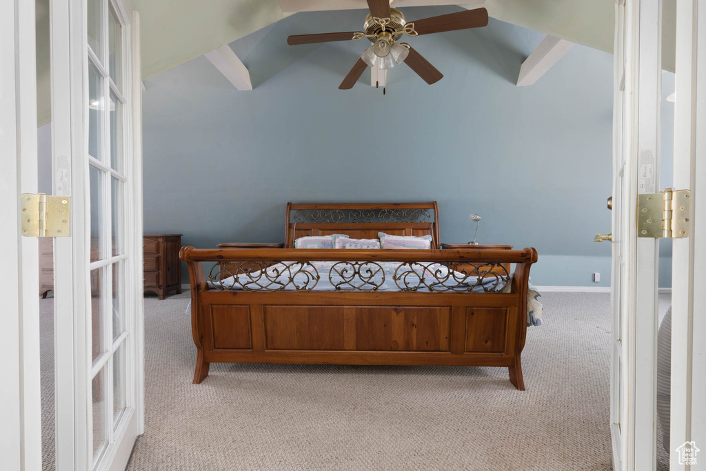 Bedroom with light carpet, ceiling fan, baseboards, and vaulted ceiling