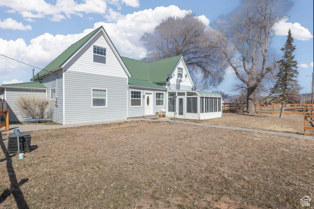 Back of property featuring metal roof, fence, and a sunroom