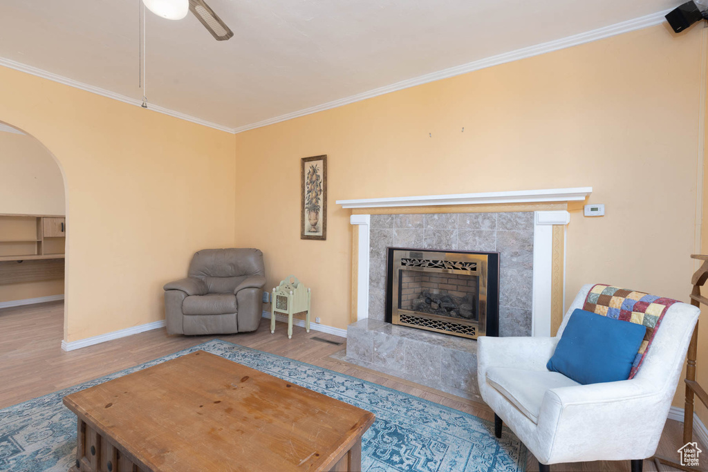 Living area featuring wood finished floors, baseboards, arched walkways, a high end fireplace, and ornamental molding