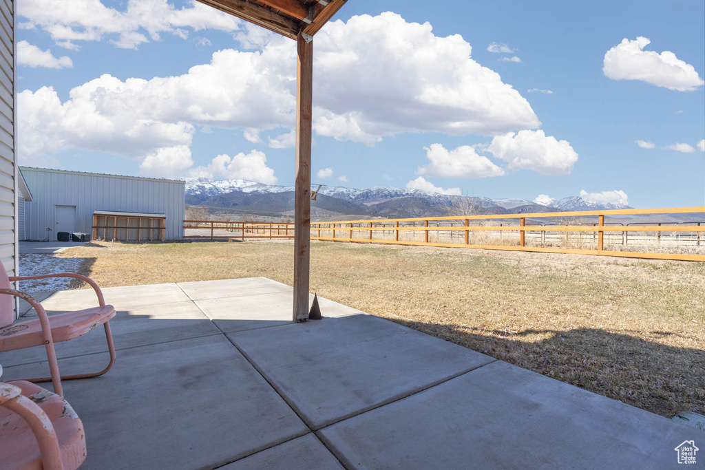 View of patio with a rural view, a mountain view, and a fenced backyard
