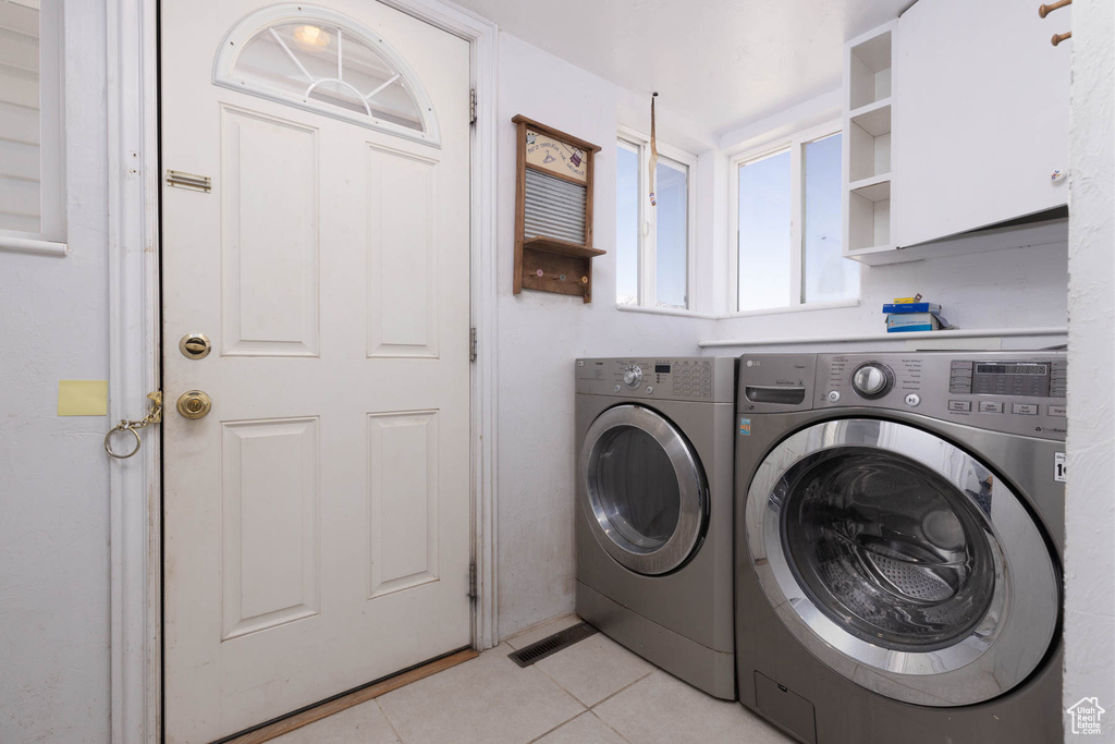 Laundry area with washer and clothes dryer and light tile patterned flooring