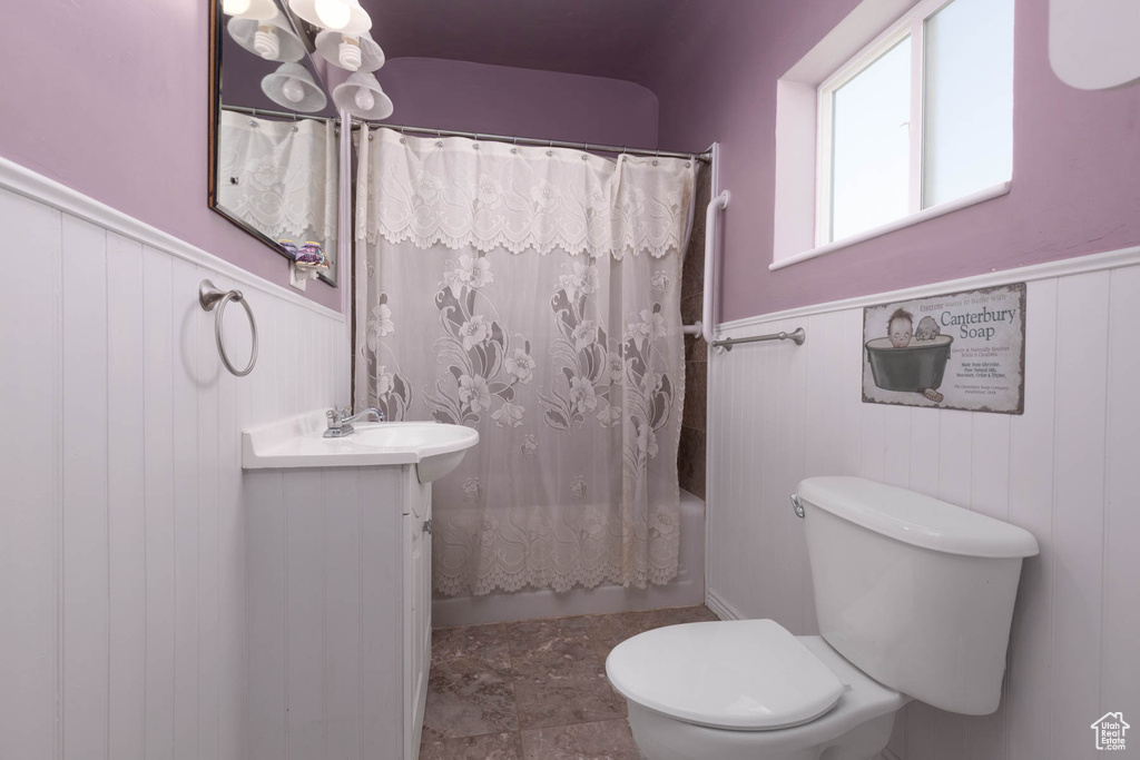 Full bath featuring wainscoting, toilet, vanity, and shower / bath combo