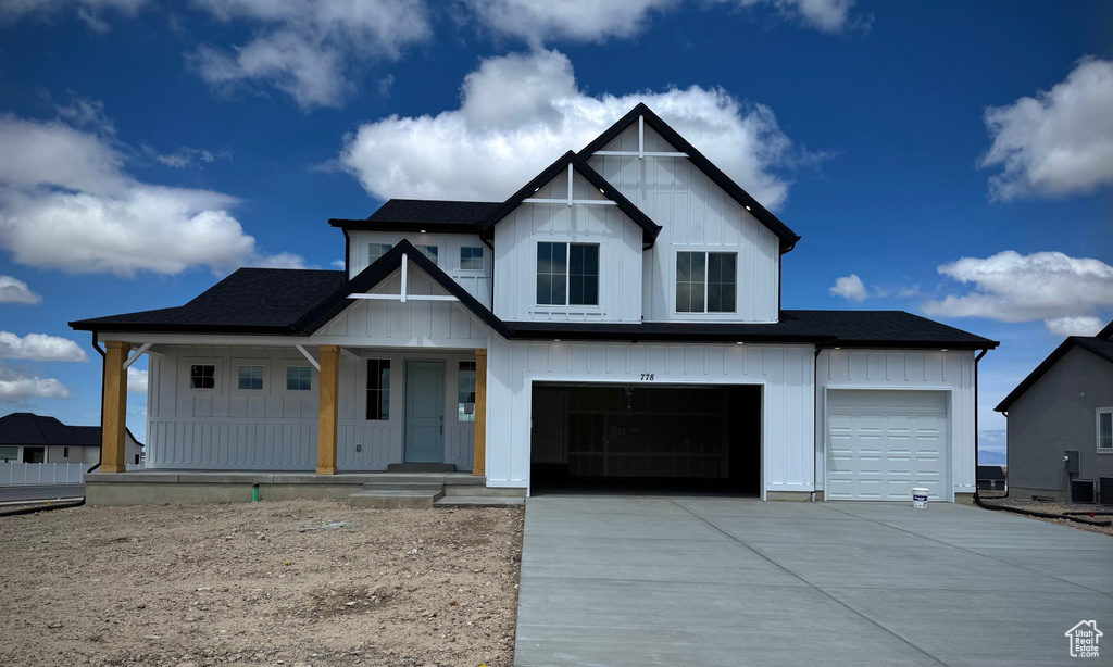 Modern farmhouse featuring covered porch, roof with shingles, an attached garage, concrete driveway, and board and batten siding