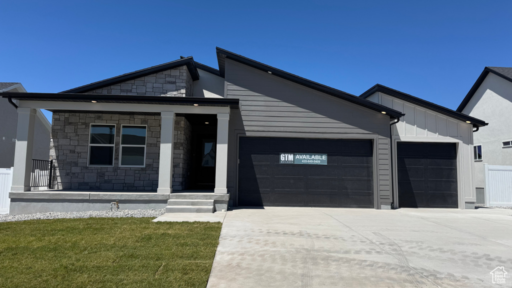 View of front of house with a garage, concrete driveway, stone siding, and board and batten siding