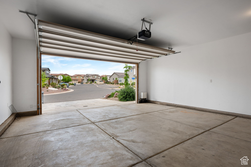 Garage featuring a residential view, a garage door opener, and baseboards