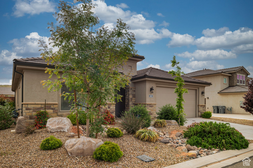View of front of property with stone siding, stucco siding, a tiled roof, and a garage