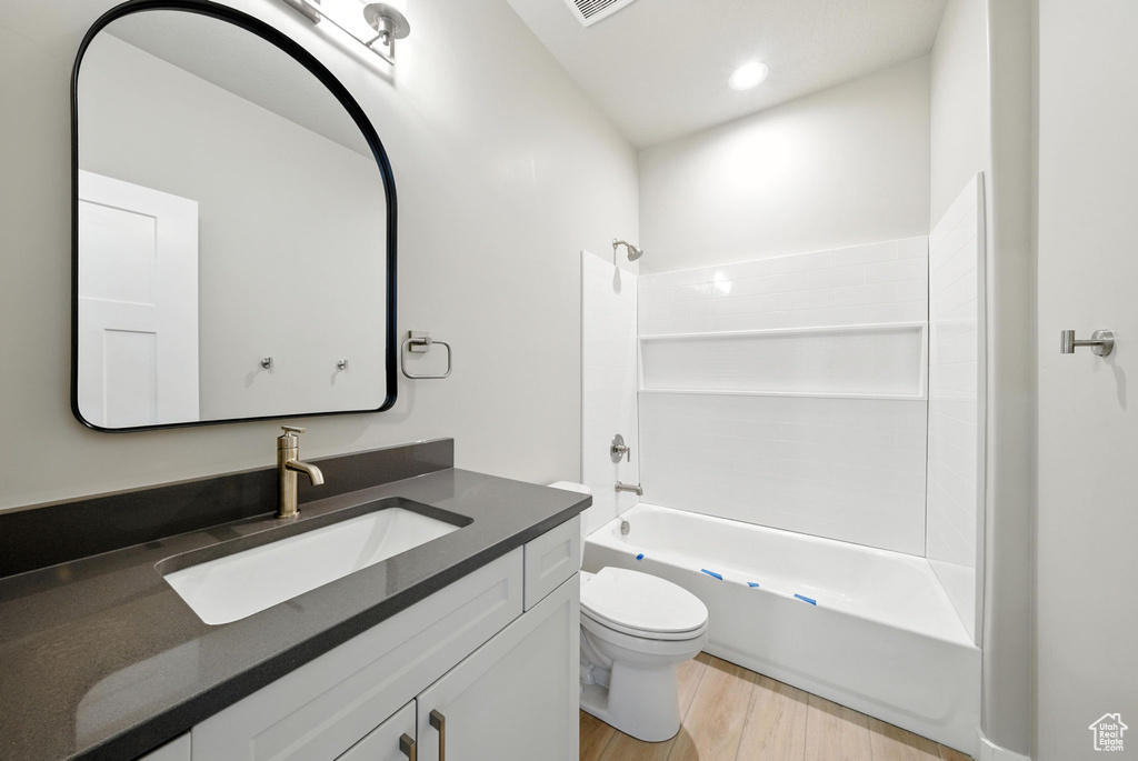 Bathroom featuring vanity, wood finished floors, and  shower combination
