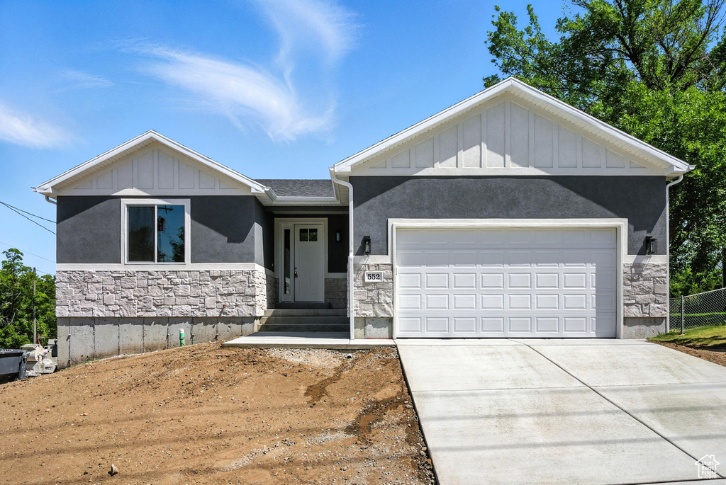 View of front of property with stone siding, board and batten siding, and driveway