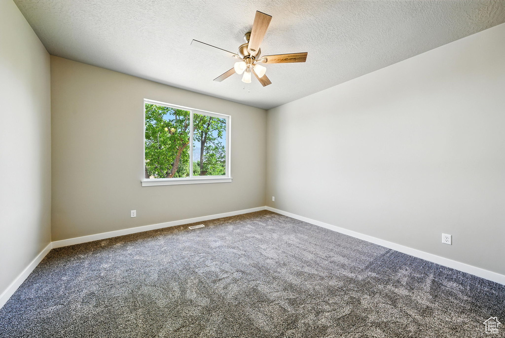 Carpeted spare room with a ceiling fan and a textured ceiling