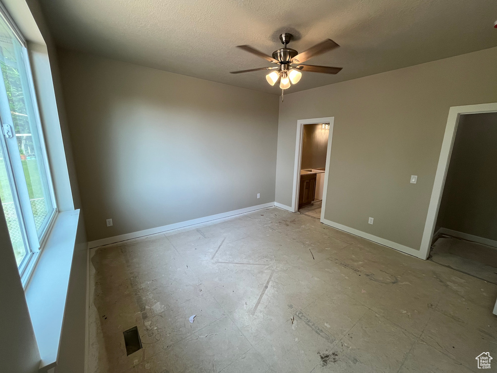 Unfurnished bedroom featuring baseboards, a textured ceiling, connected bathroom, and ceiling fan