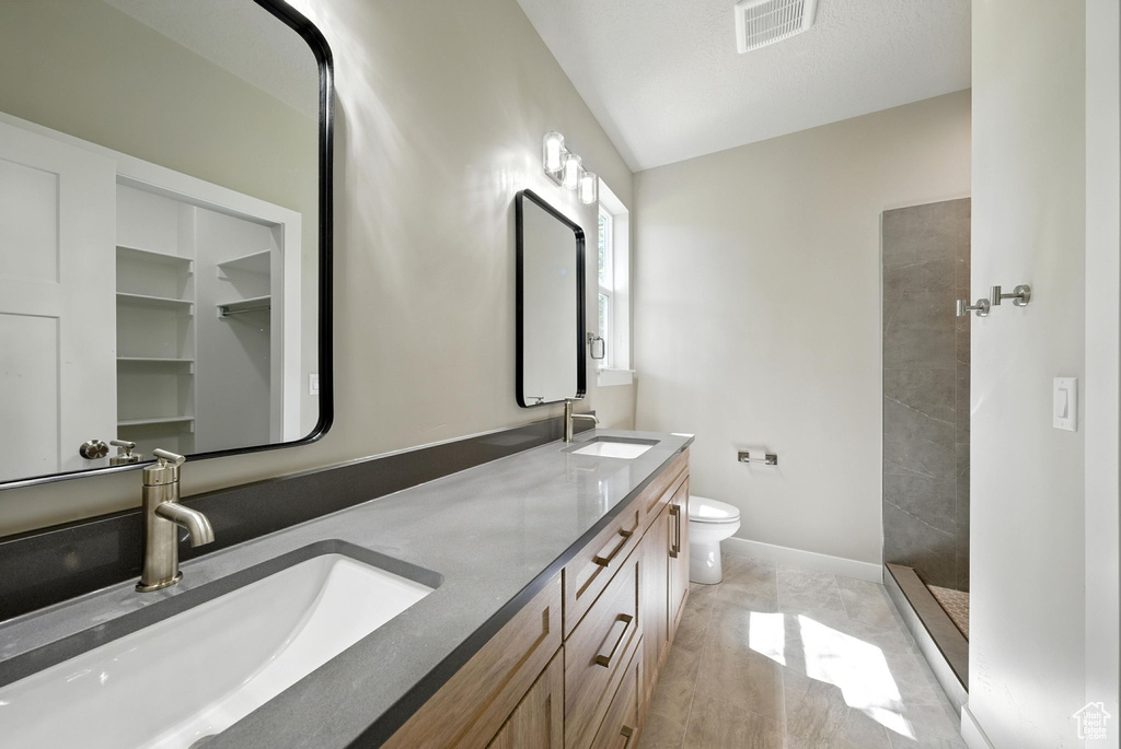 Full bathroom with double vanity and tiled shower