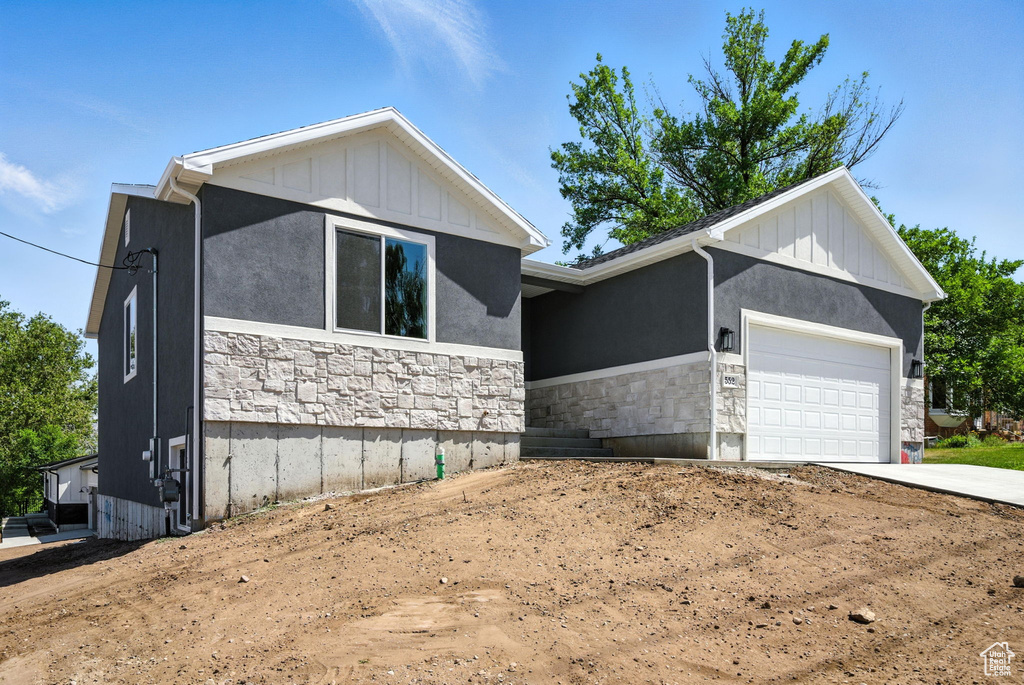Ranch-style house with stone siding, a garage, driveway, and board and batten siding