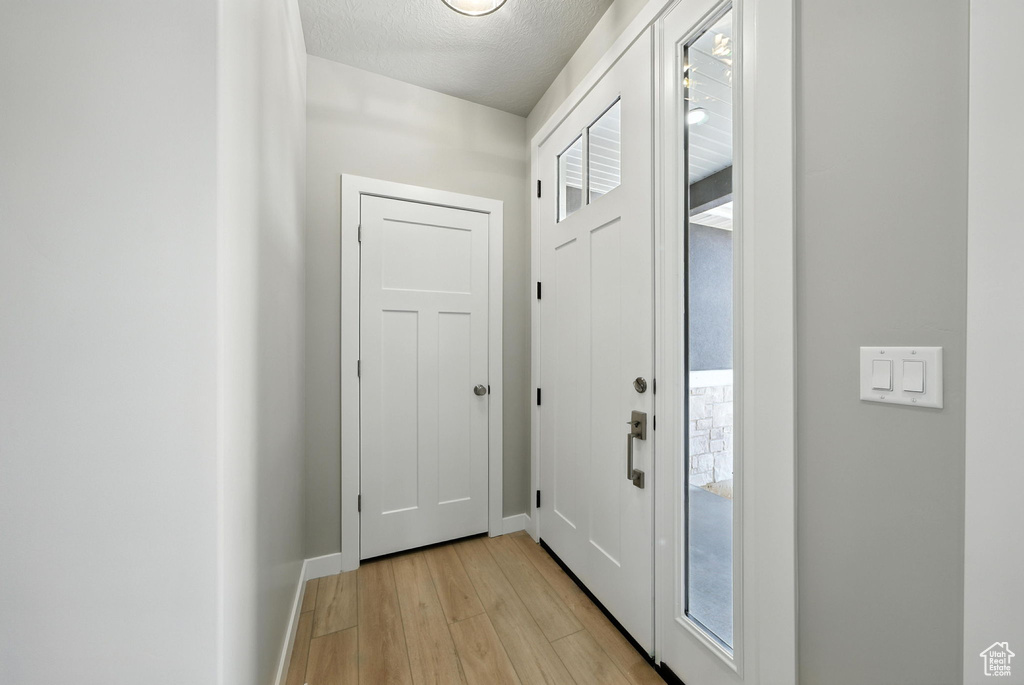 Doorway featuring light wood-type flooring and a textured ceiling
