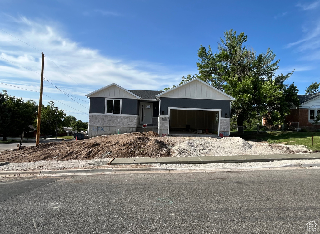 View of front of property featuring stone siding, an attached garage, and driveway