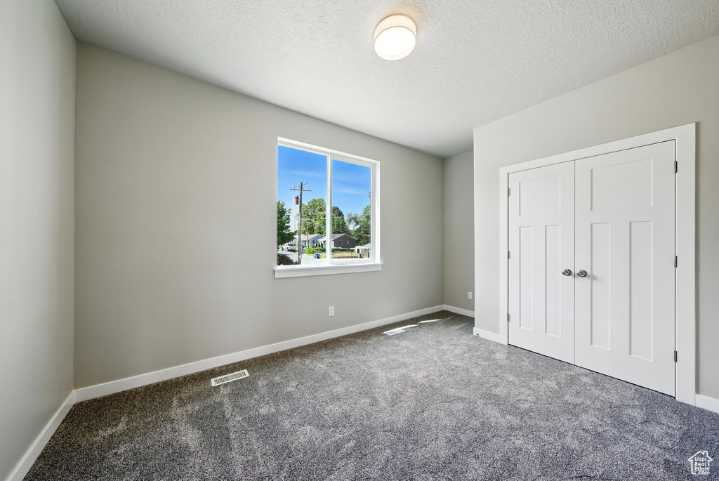 Unfurnished bedroom featuring carpet, a closet, and a textured ceiling