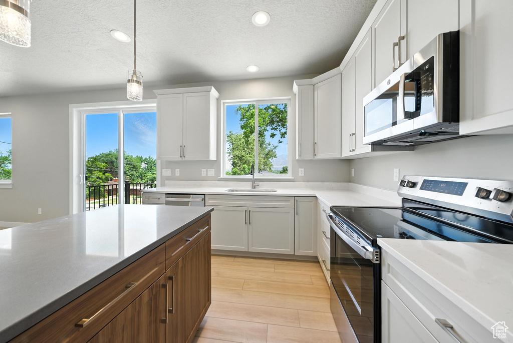 Kitchen with stainless steel appliances, recessed lighting, a textured ceiling, white cabinets, and pendant lighting