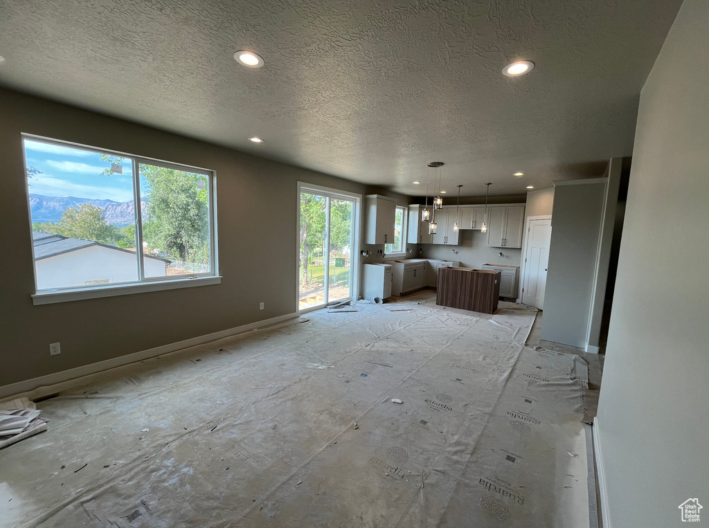 Unfurnished living room with a textured ceiling, recessed lighting, and baseboards