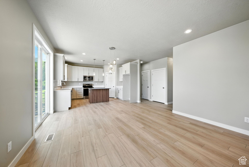 Unfurnished living room with light wood-type flooring, recessed lighting, and a textured ceiling