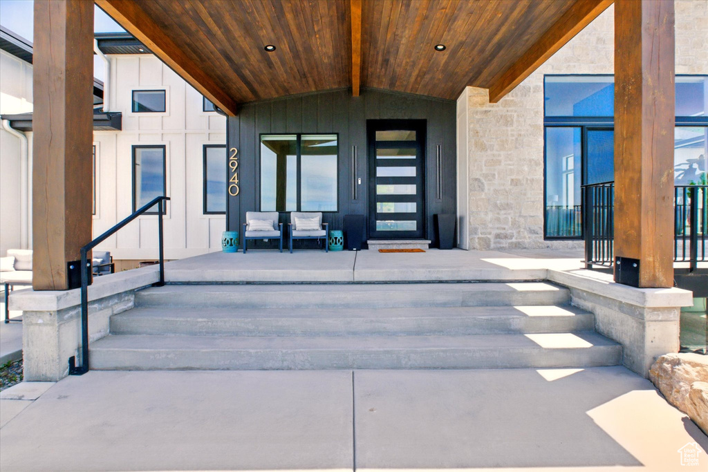 Doorway to property featuring stone siding, board and batten siding, and a porch