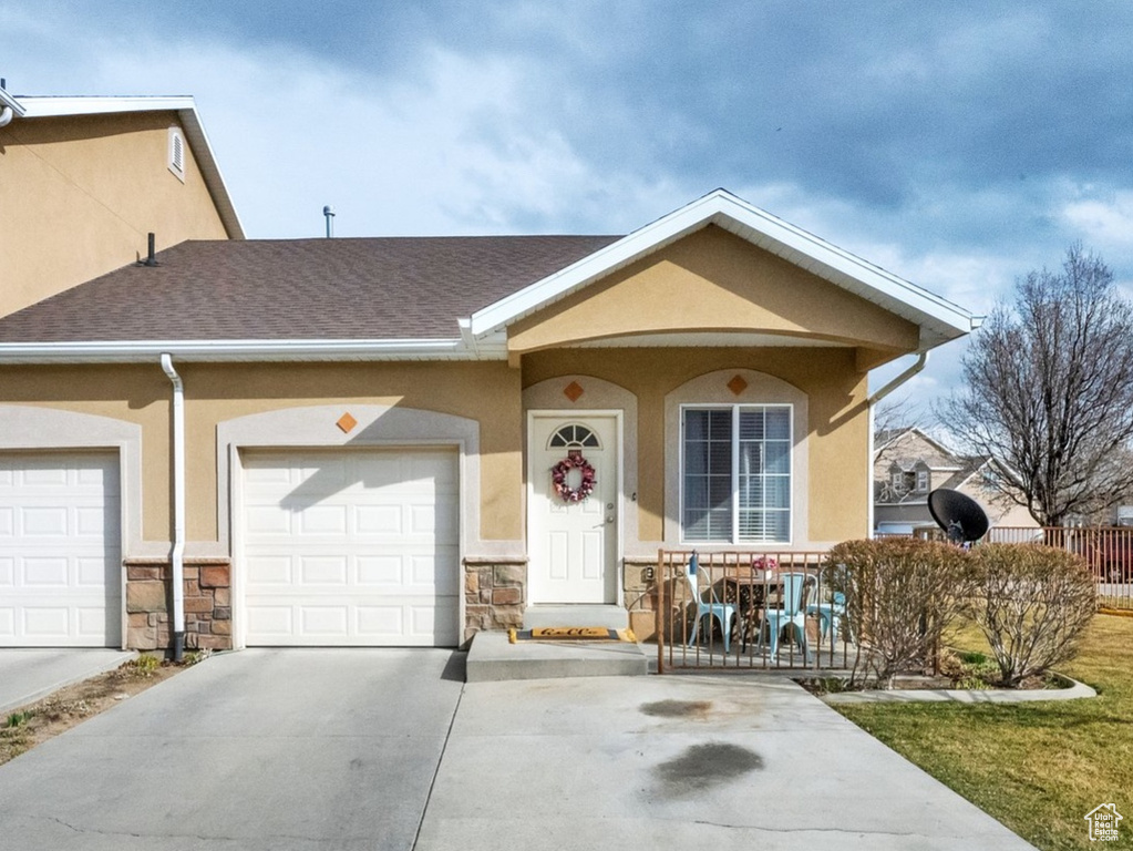 View of front of house featuring a front lawn, fence, stucco siding, stone siding, and driveway