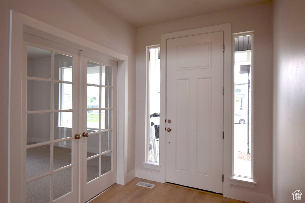 Foyer with french doors and light wood-style floors