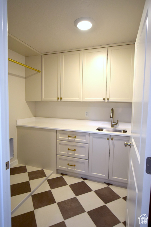 Kitchen with a sink, light floors, light countertops, and white cabinets