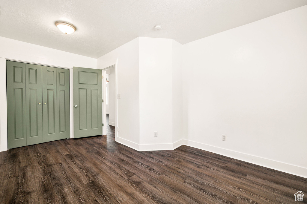 Unfurnished bedroom featuring dark wood-style flooring, baseboards, and a closet