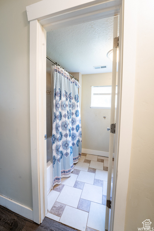 Full bathroom featuring baseboards, visible vents, shower / bathtub combination with curtain, and a textured ceiling