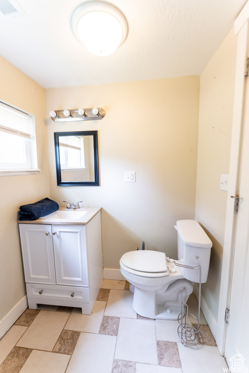 Half bathroom featuring baseboards, toilet, and vanity
