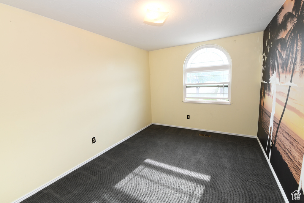Empty room with dark colored carpet and baseboards