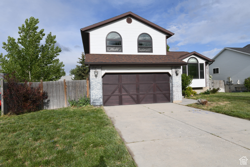 Traditional home with driveway, a garage, brick siding, and roof with shingles