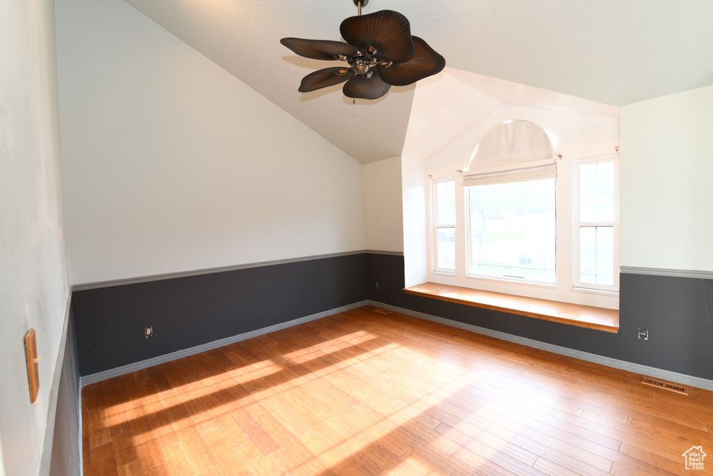 Spare room with wood finished floors, lofted ceiling, ceiling fan, and baseboards