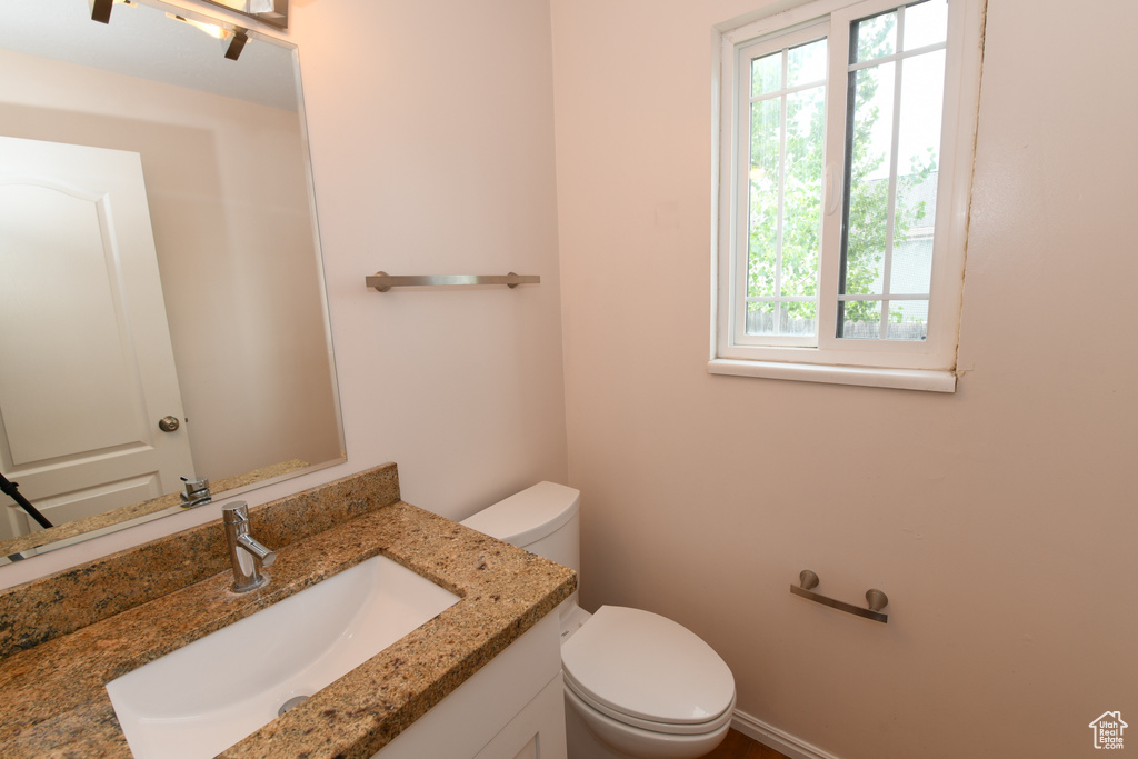 Bathroom featuring healthy amount of natural light, toilet, and vanity
