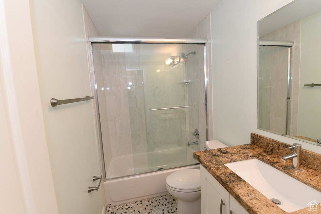 Full bathroom with toilet, vanity, and bath / shower combo with glass door