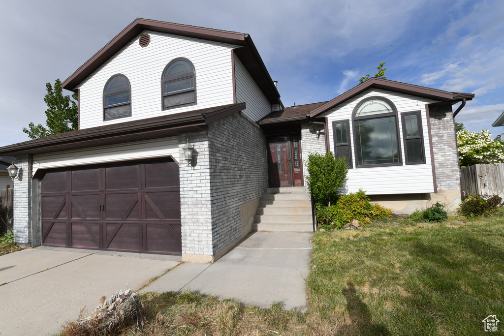 View of front facade featuring a garage, brick siding, and driveway