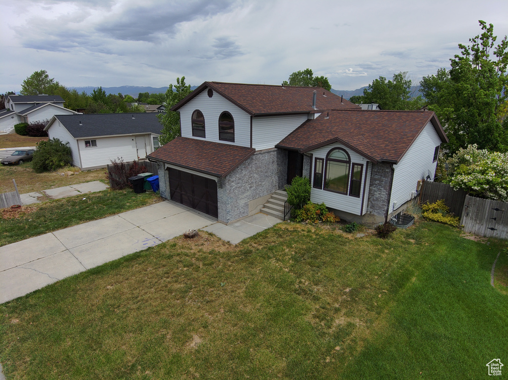 Traditional-style house featuring concrete driveway, roof with shingles, an attached garage, and a mountain view