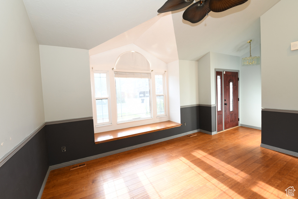 Unfurnished room featuring wood finished floors, vaulted ceiling, a ceiling fan, and baseboards